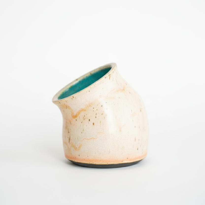 Small ceramic vase with a textured beige exterior and teal interior on a white background